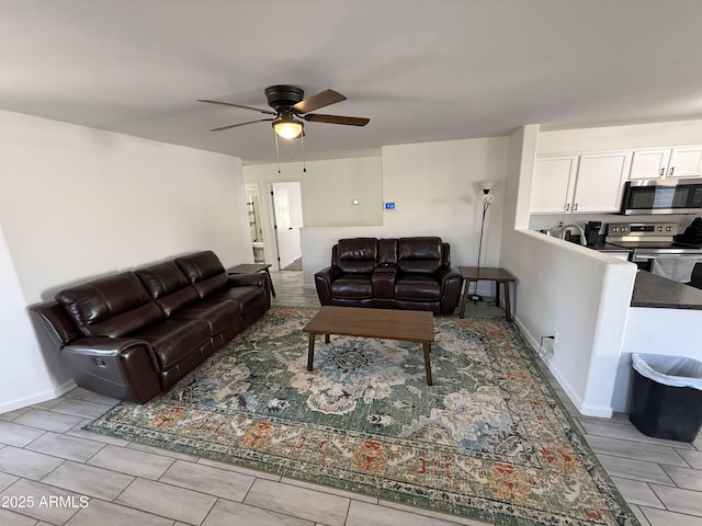 living room with a ceiling fan and baseboards