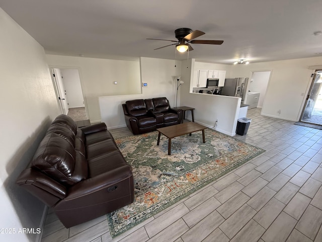 living room with wood finish floors, ceiling fan, and baseboards