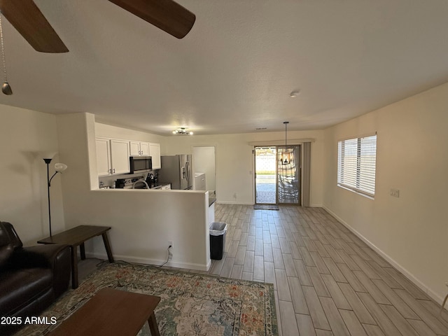 living area with light wood finished floors, a ceiling fan, and baseboards