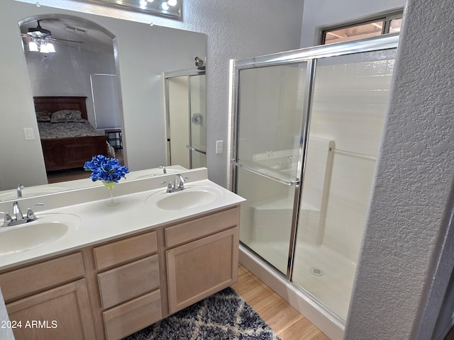 bathroom with hardwood / wood-style floors, ceiling fan, walk in shower, and vanity