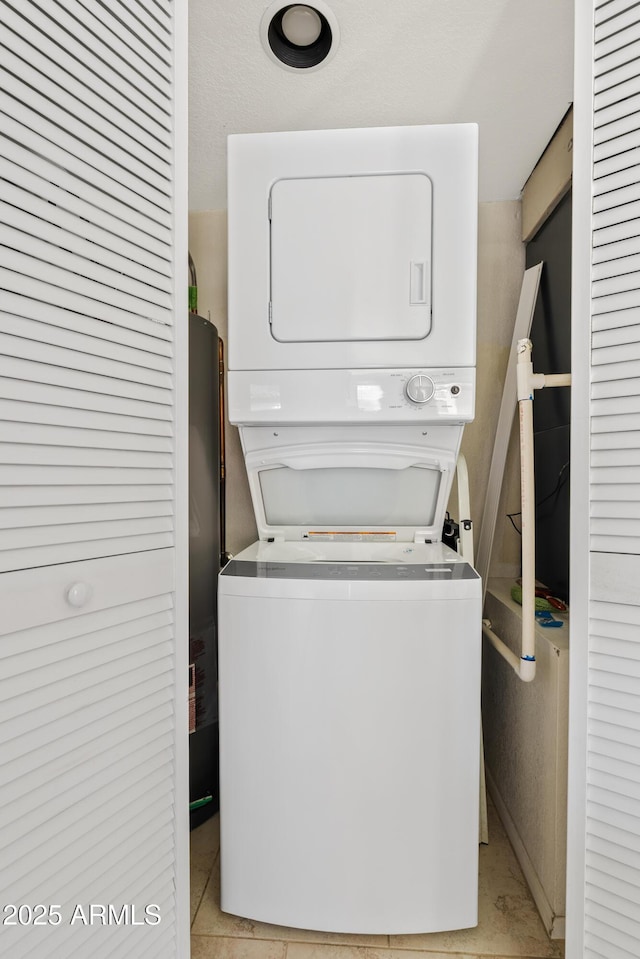 clothes washing area featuring light tile patterned flooring and stacked washer and clothes dryer