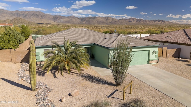 view of front of property with a garage, a tile roof, fence, and a mountain view