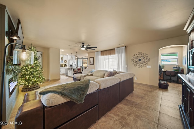 living area with light tile patterned flooring, plenty of natural light, baseboards, and ceiling fan