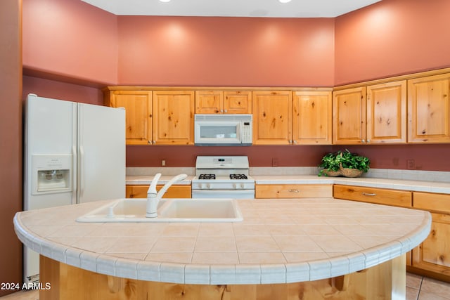 kitchen featuring white appliances, tile countertops, a kitchen island with sink, and sink