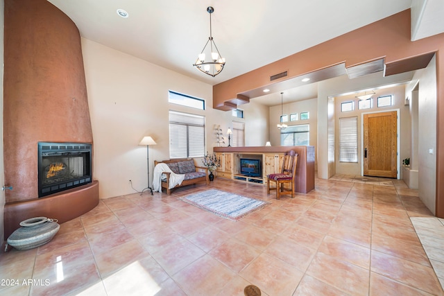 entrance foyer with light tile patterned floors, a large fireplace, and a notable chandelier