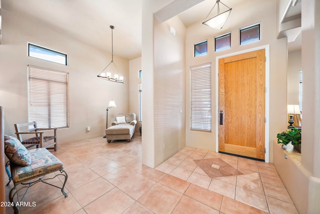 foyer with light tile patterned floors, a towering ceiling, and an inviting chandelier