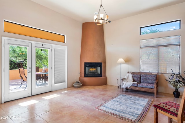 living area featuring a large fireplace, light tile patterned flooring, french doors, and an inviting chandelier