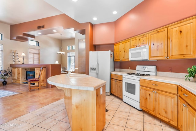 kitchen featuring tile counters, a center island, sink, decorative light fixtures, and white appliances