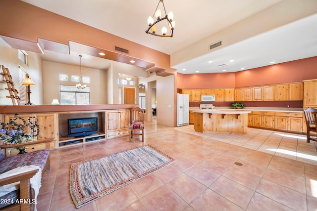 kitchen with white appliances, decorative light fixtures, a chandelier, a center island, and a breakfast bar area