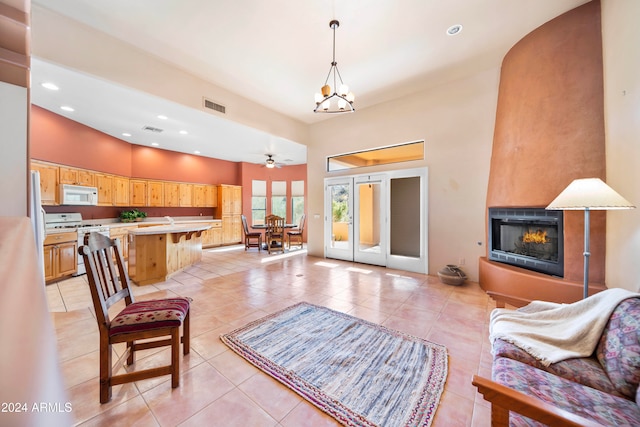 tiled living room with a fireplace and ceiling fan with notable chandelier