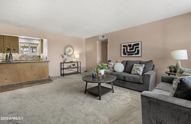 living room featuring a textured ceiling, carpet floors, and visible vents