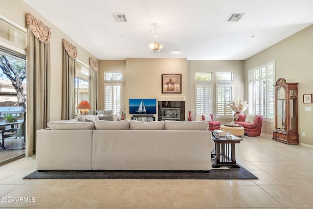 living room featuring a chandelier, light tile patterned floors, a fireplace, and a healthy amount of sunlight