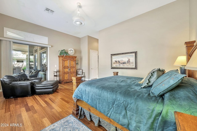 bedroom with wood-type flooring, access to outside, and ceiling fan