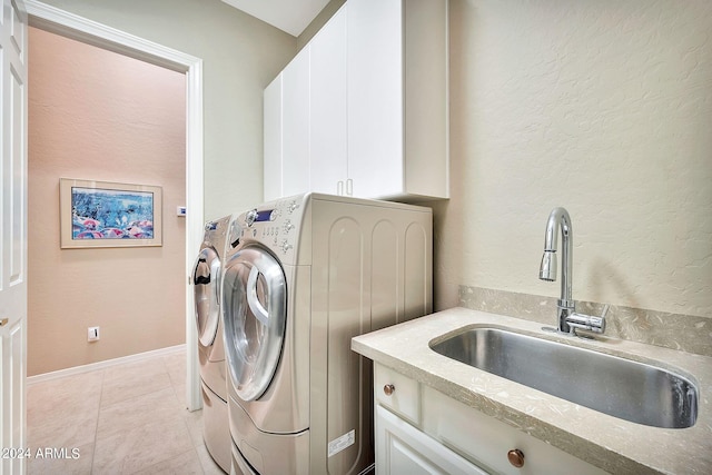 washroom with light tile patterned floors, sink, washer and dryer, and cabinets