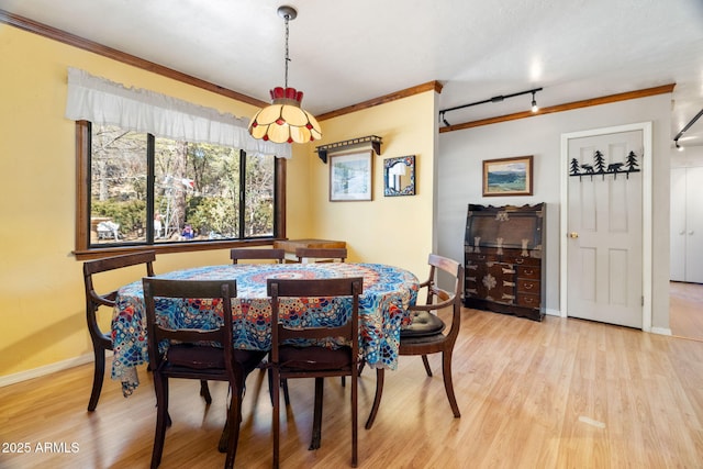 dining area featuring light hardwood / wood-style floors, track lighting, and ornamental molding