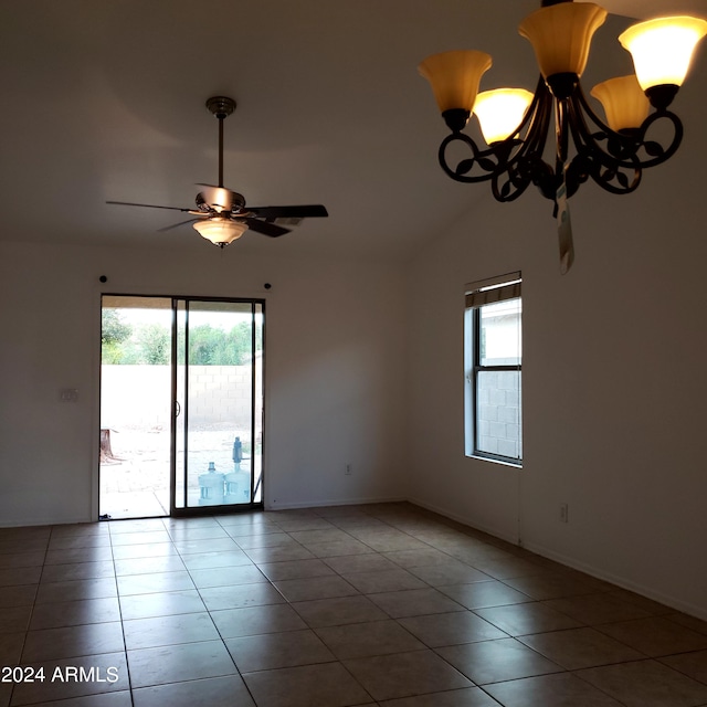 tiled spare room with ceiling fan with notable chandelier and a healthy amount of sunlight