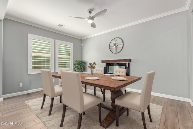 dining area with crown molding, light wood-style floors, baseboards, and visible vents