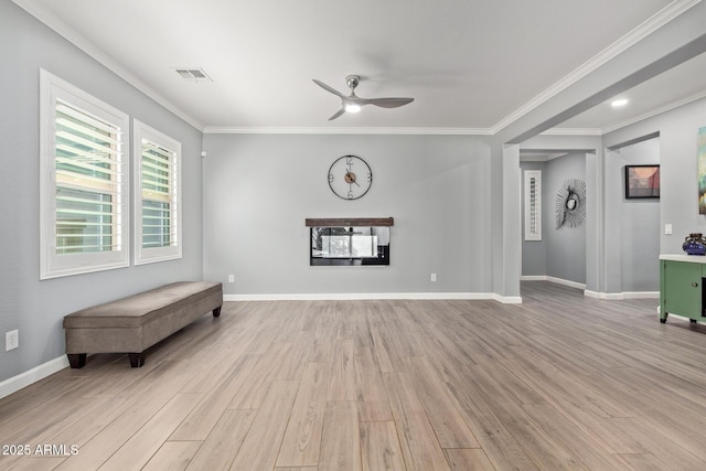 unfurnished room with a glass covered fireplace, light wood-style flooring, baseboards, and ornamental molding