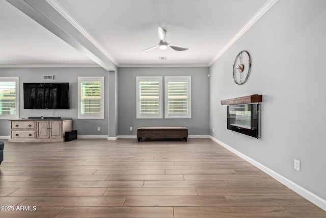 unfurnished living room with plenty of natural light, wood finished floors, baseboards, and ceiling fan