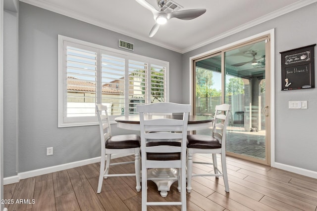 dining area featuring wood finished floors, baseboards, visible vents, ornamental molding, and ceiling fan