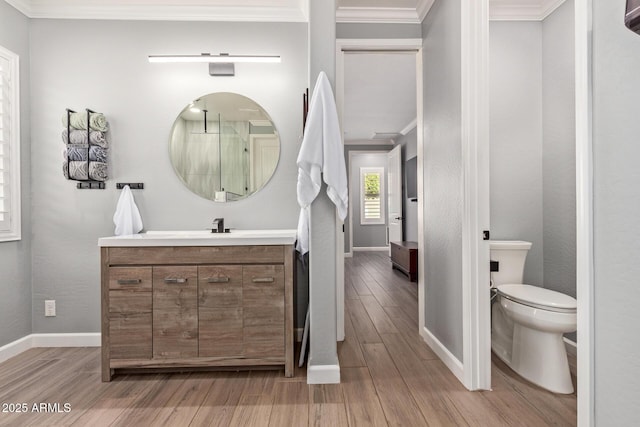 bathroom featuring vanity, wood finished floors, baseboards, ornamental molding, and toilet