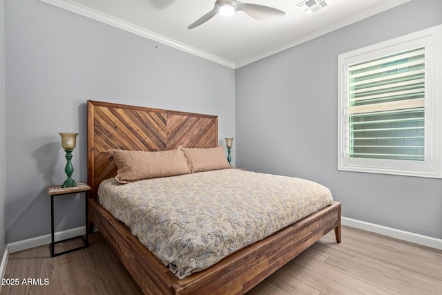 bedroom featuring visible vents, wood finished floors, baseboards, and ornamental molding