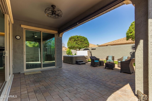 view of patio / terrace with a fenced backyard, a fire pit, and a hot tub