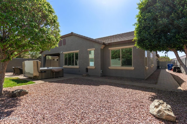 rear view of house with a patio, a fenced backyard, stucco siding, a hot tub, and a tile roof