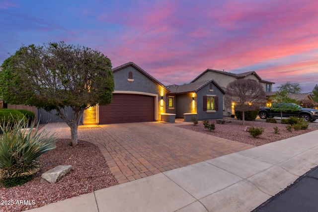 ranch-style home featuring a tiled roof, decorative driveway, an attached garage, and stucco siding