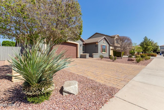 view of front of house featuring fence, a tile roof, stucco siding, decorative driveway, and an attached garage