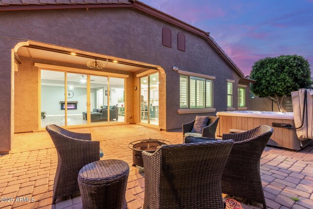 view of patio / terrace featuring an outdoor fire pit, fence, and a hot tub