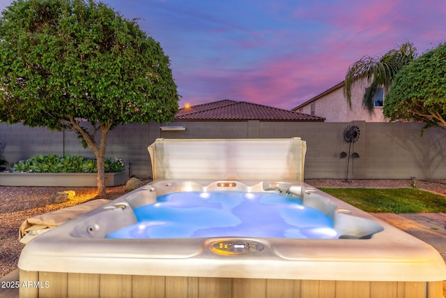 view of patio / terrace featuring an attached garage, a fenced backyard, and a hot tub