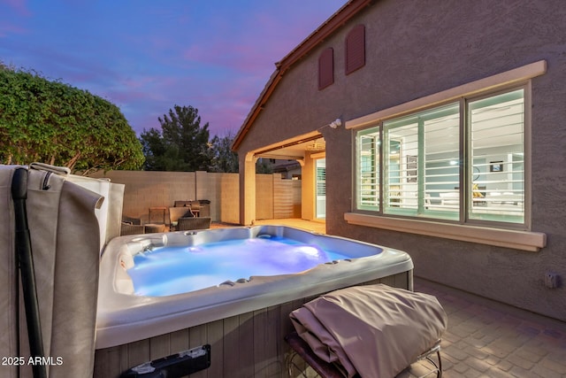 view of patio featuring an outdoor hot tub and fence