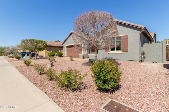 view of front of home featuring stucco siding, a tile roof, fence, concrete driveway, and a garage