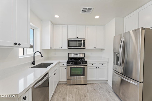 kitchen with sink, appliances with stainless steel finishes, light wood-type flooring, and white cabinets