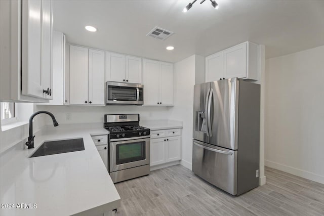 kitchen featuring sink, white cabinetry, stainless steel appliances, and light wood-type flooring