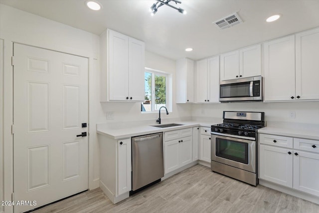 kitchen featuring appliances with stainless steel finishes, white cabinets, and light hardwood / wood-style floors