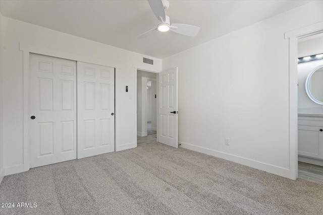 unfurnished bedroom featuring ceiling fan, ensuite bathroom, a closet, and light colored carpet