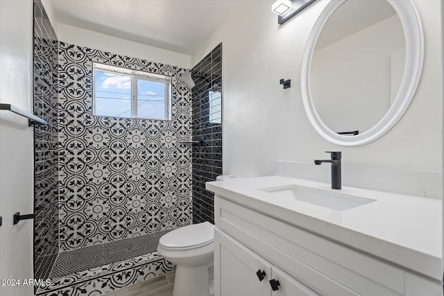 bathroom with vanity, tiled shower, and toilet