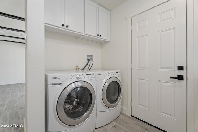 laundry room featuring washing machine and dryer, light wood-type flooring, and cabinets