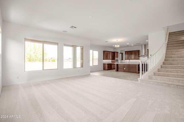 unfurnished living room with light colored carpet and a chandelier