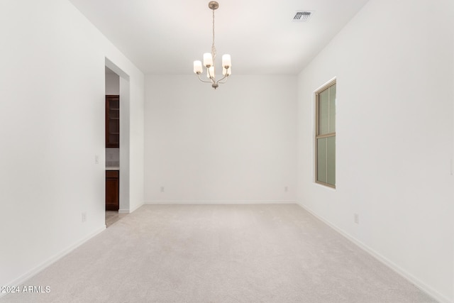 unfurnished room featuring light colored carpet and a notable chandelier