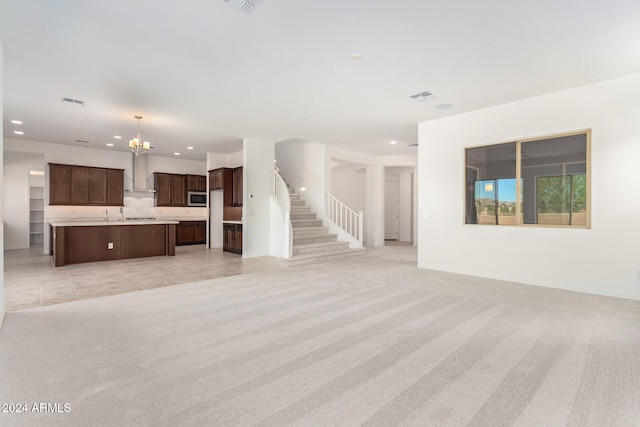 unfurnished living room featuring a chandelier and light carpet