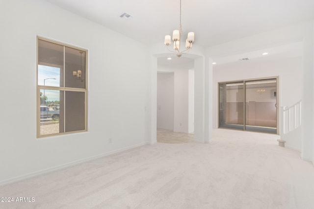 carpeted spare room with a chandelier