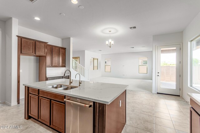 kitchen with light stone countertops, sink, dishwasher, a chandelier, and a kitchen island with sink