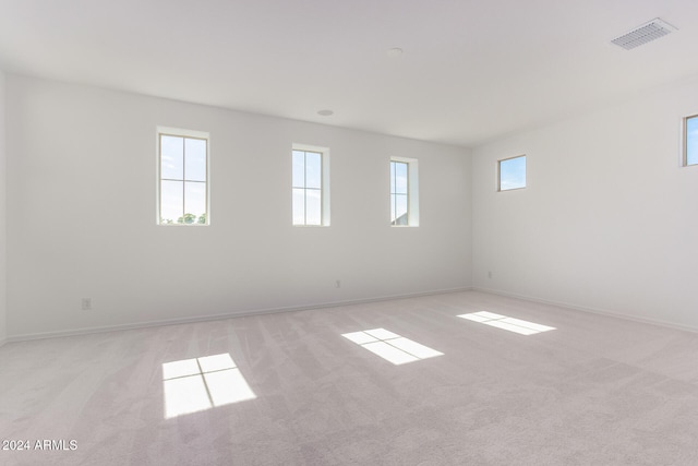 unfurnished room with light colored carpet and a healthy amount of sunlight