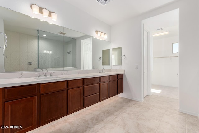 8628 W Solano Dr, Glendale, AZ 85305 - bathroom with tiled shower, double vanity, a walk in closet, and baseboards
