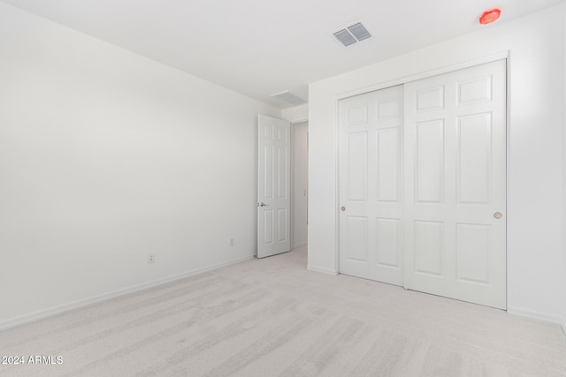 unfurnished bedroom with light carpet and a closet