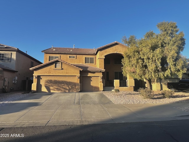 mediterranean / spanish house with an attached garage, stucco siding, concrete driveway, and a tiled roof