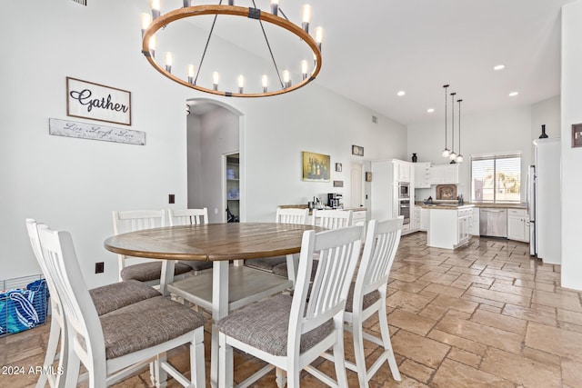 2731 W Desert Ranch Rd, Phoenix, AZ 85086 - dining area featuring a high ceiling, arched walkways, stone tile flooring, a chandelier, and recessed lighting